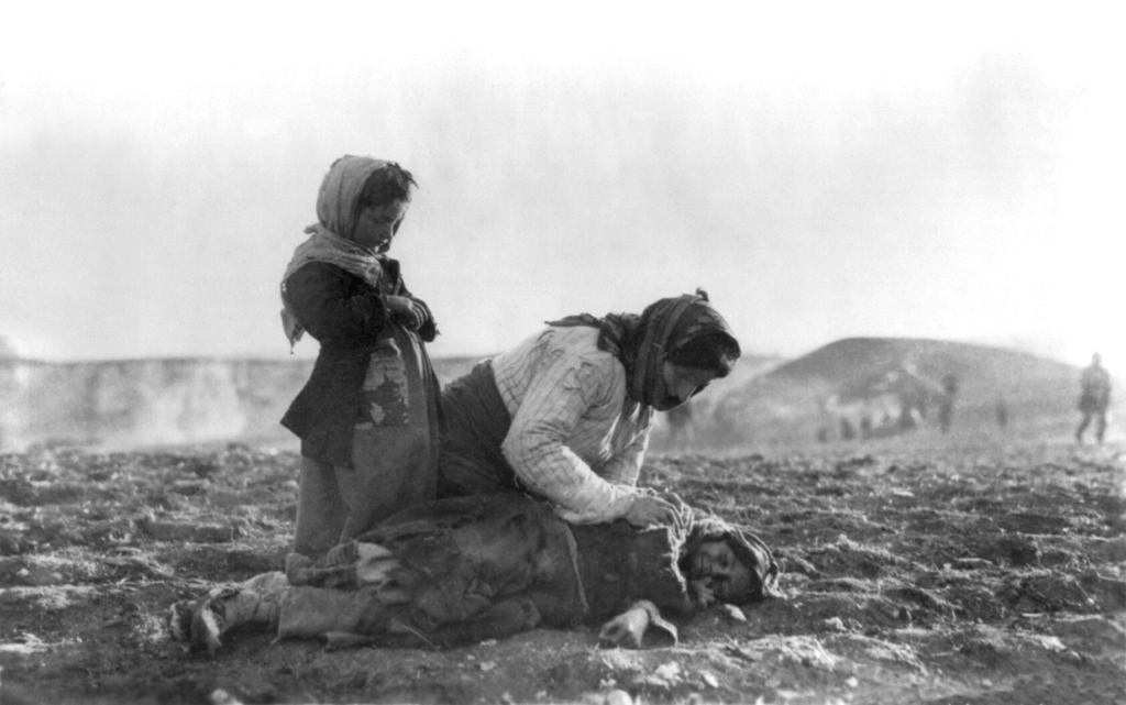 Armenian woman kneeling beside dead child in field, approx. 1917; photo Public Domain, Library of Congress 