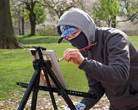 An artist in Central Park, New York, adheres to citywide face-covering policy even in the middle of a traditionally solitary endeavor; photo by Jane Feldman.