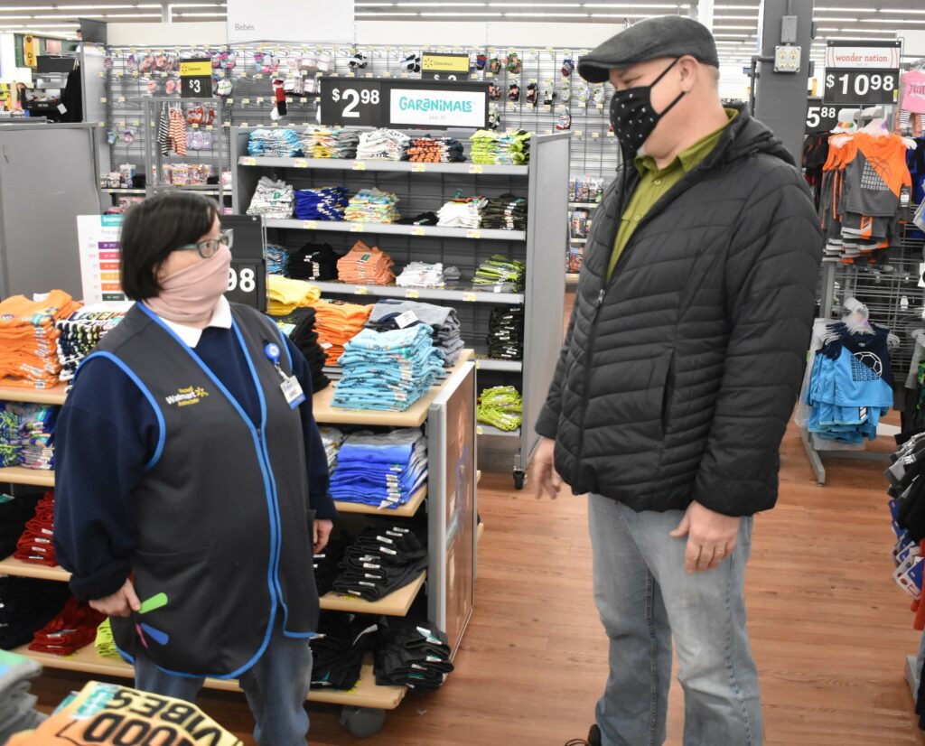 Photo of a woman and man, masked, standing in the middle of the children's clothing section in a department store.