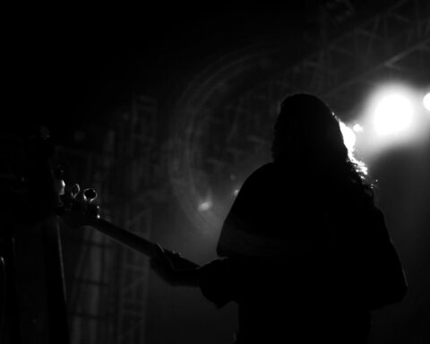 Silhouetted guitarist performing under stage lights during an intimate live music set