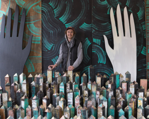 Artist Wes Bruce stands among sculptural installation elements as part of his immersive community-centered artistic practice.