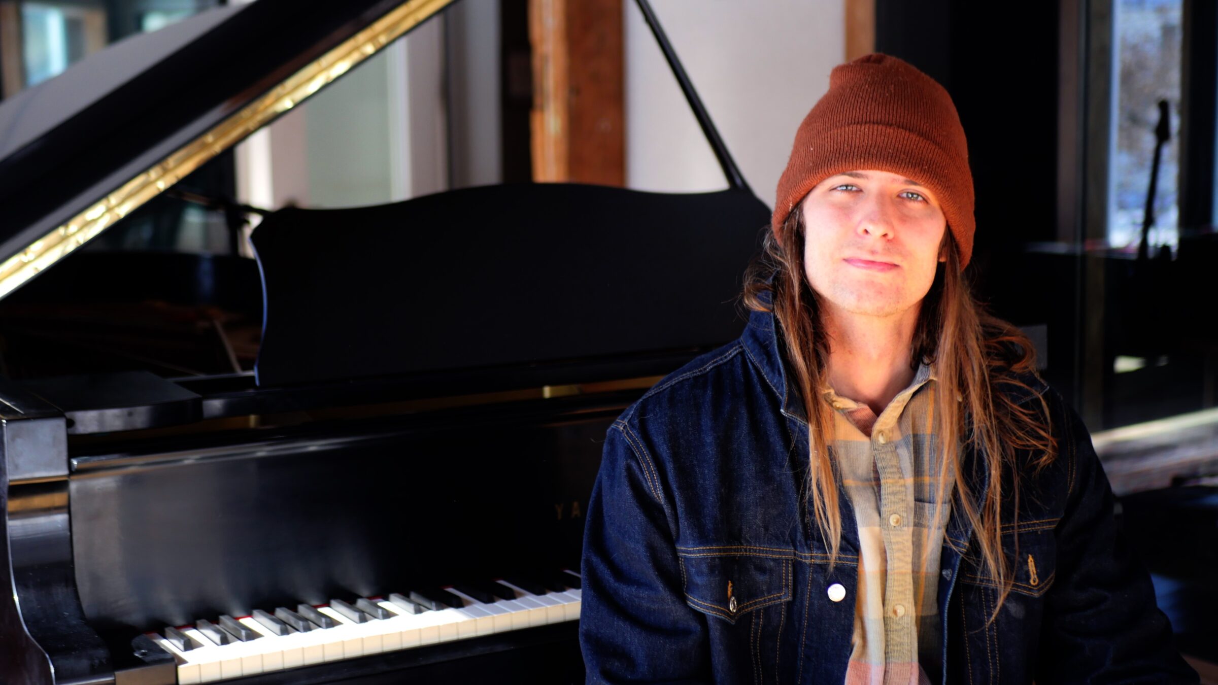 Vermont musician, radio host, and recovery advocate Benjamin Lerner sits beside a grand piano ahead of his 24-hour CLEAN Jam radiothon celebrating 10 years of sobriety.